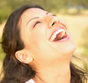 Laughing woman outdoors, head tilted back