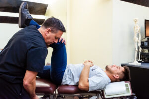Chiropractor stretching patient's leg on treatment table